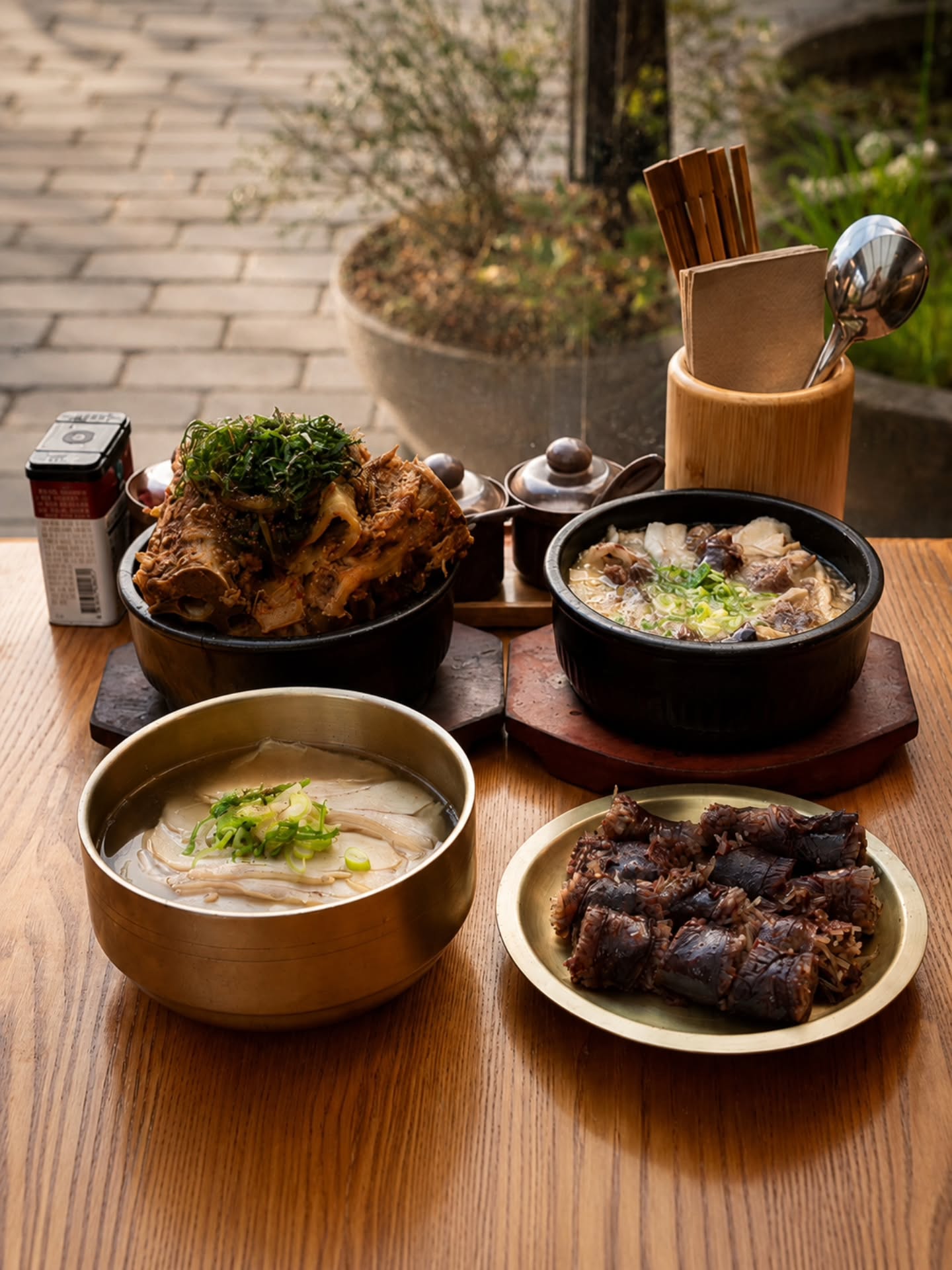 A table spread at Dweji: jokbal, gukbap, soondaeguk, and house-made soondae on an outdoor patio table